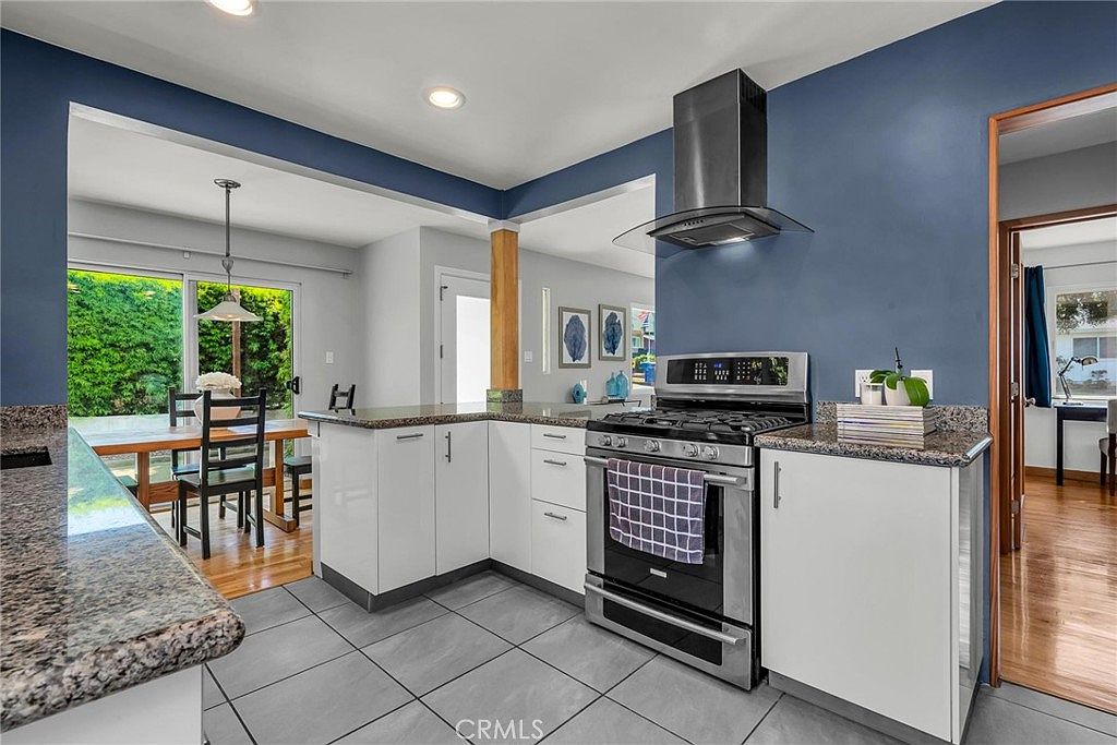 Kitchen with deep blue accent wall, stainless range, and granite counters.