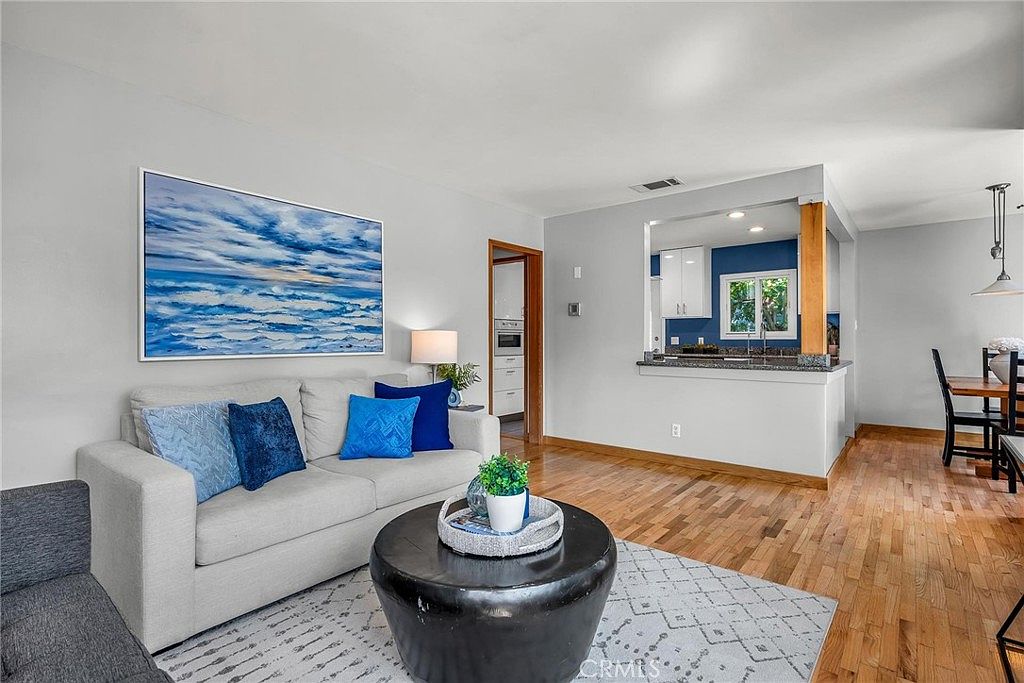 Second living area with textile sofa, art, and hardwood floors.
